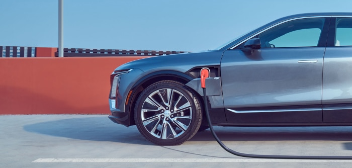 Electric car charging at a station with a sleek gray design against a sunny backdrop.