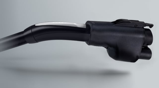 Close-up of an electric vehicle charging connector against a gray background.