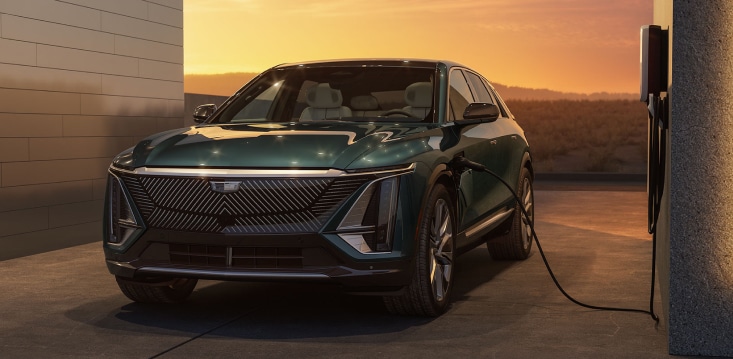 Electric SUV charging at a station during sunset.
