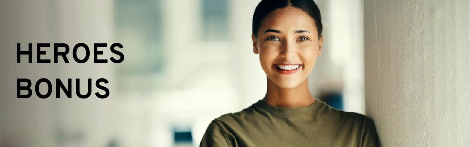Smiling woman standing by a wall with the text "Heroes Bonus" beside her.