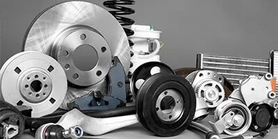 Assorted car parts including brake discs, springs, and gears are arranged on a gray background.