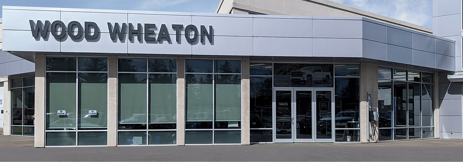 Car dealership exterior with "Wood Wheaton" signage, large windows, and sales entrance.